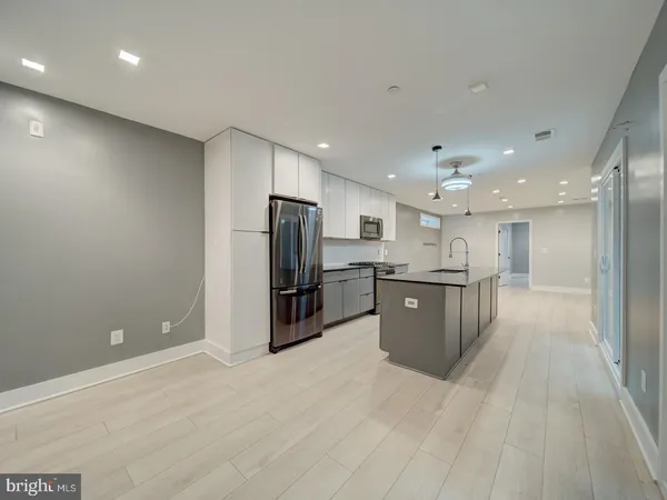 a large kitchen with stainless steel appliances kitchen island a large counter top and a refrigerator