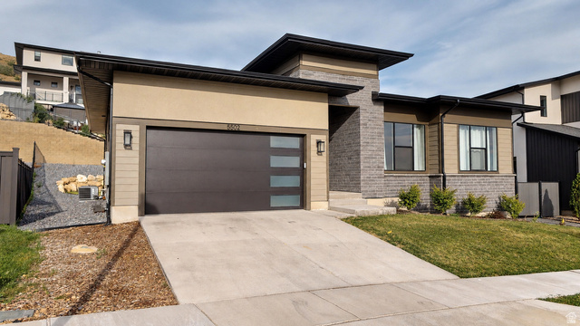 5502 North Valley View Road Lehi, UT 84048 - Photo 2 of 33 Modern exterior featuring a dark bronze garage door with frosted glass panels, stucco and brick facade, and a concrete driveway