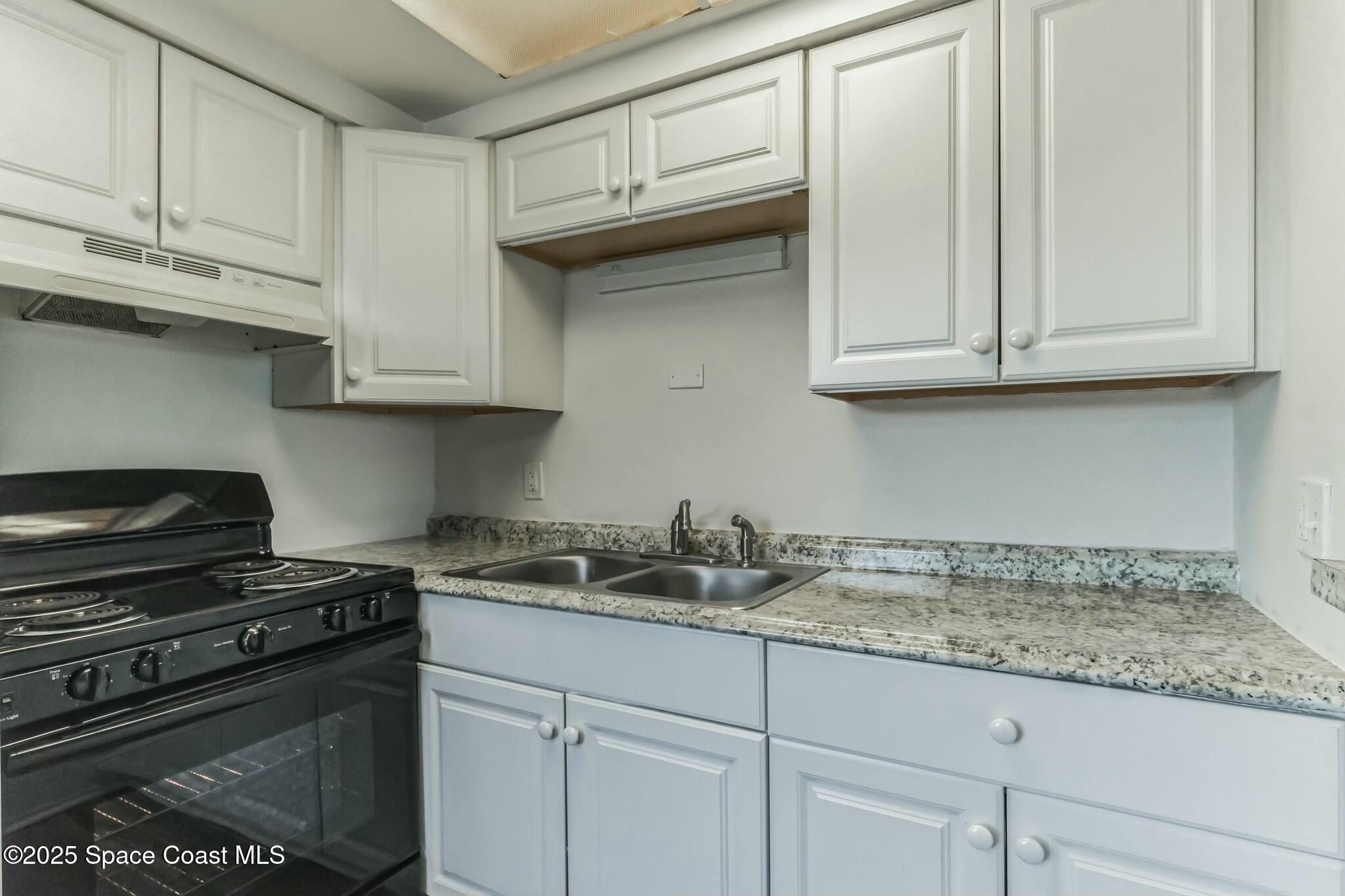 800 North Fiske Boulevard, Unit 513 Cocoa, FL 32922 - Photo 12 of 21 a kitchen with granite countertop white cabinets and a stove top oven