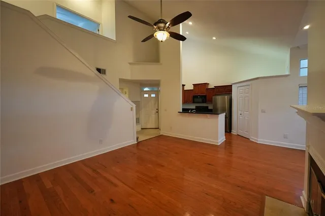 a view of a big room with wooden floor a ceiling fan and staircase