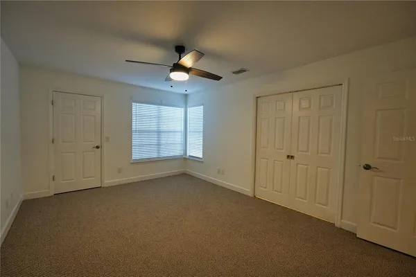 an empty room with windows and fan