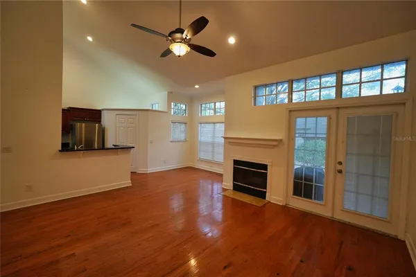 an empty room with windows fireplace and wooden floor