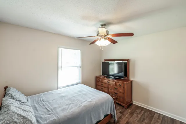 a bedroom with a large bed a flat tv screen and a fan