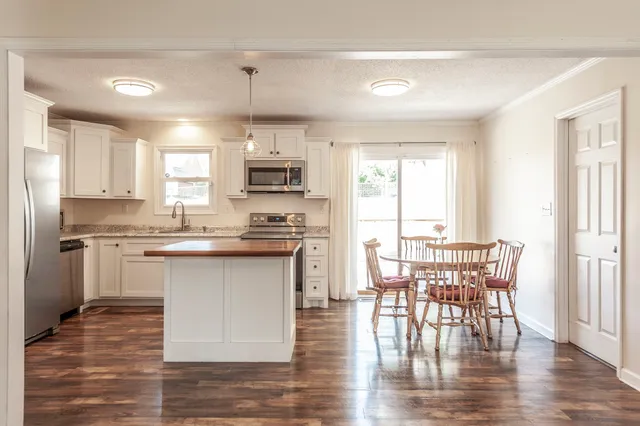 a kitchen with kitchen island granite countertop a sink cabinets and wooden floor