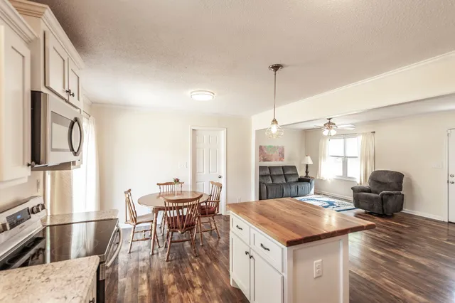 a kitchen with stainless steel appliances kitchen island granite countertop a table chairs and a refrigerator