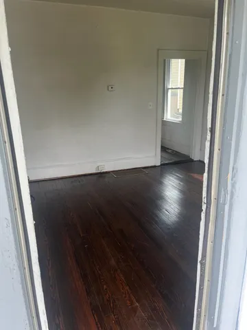 an empty room with wooden floor and windows with curtains