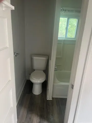 a white toilet sitting in a bathroom next to a window