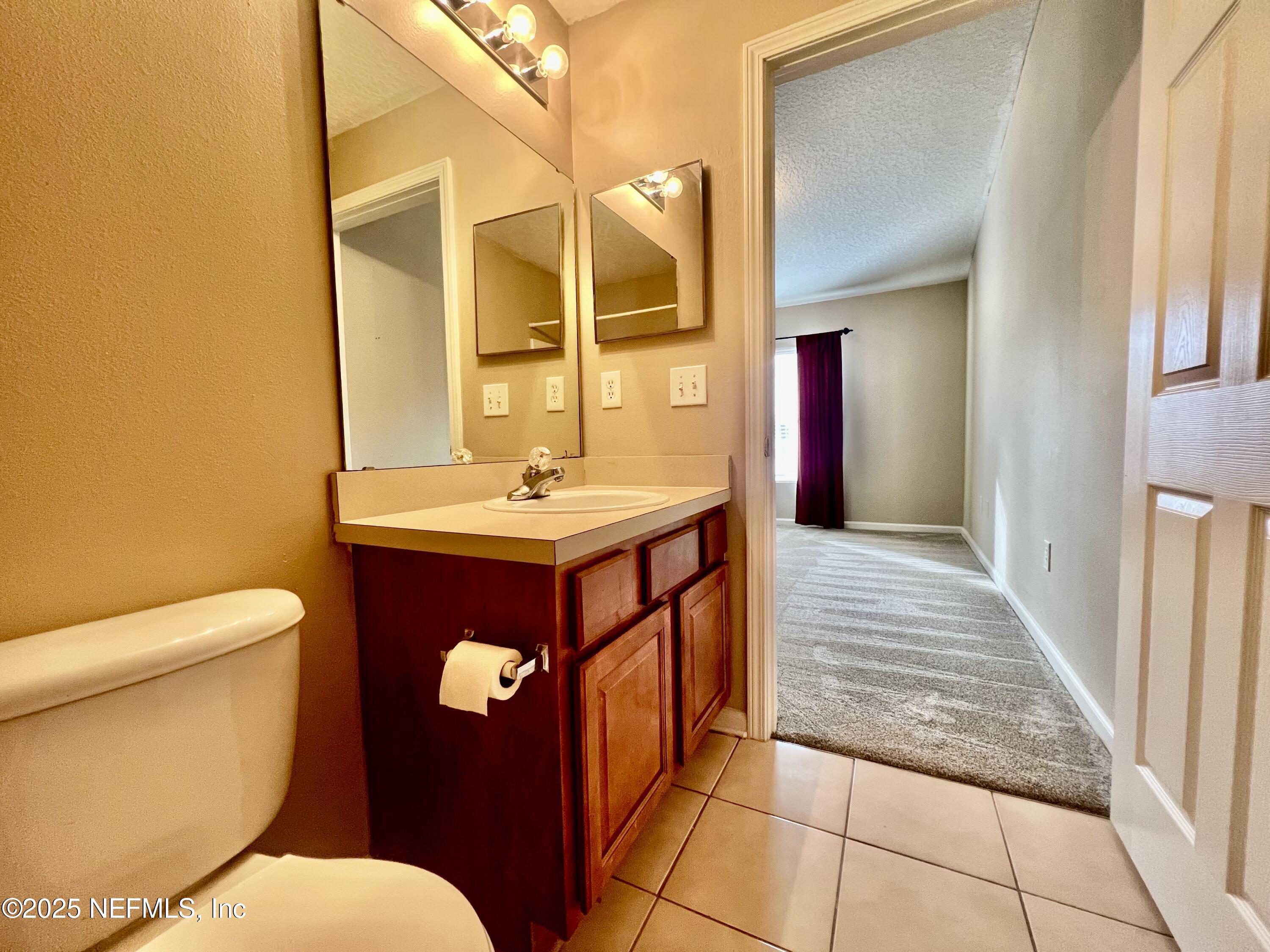 7920 Merrill Road, Unit 709 Jacksonville, FL 32277 - Photo 25 of 35 a bathroom with a sink a toilet and mirror