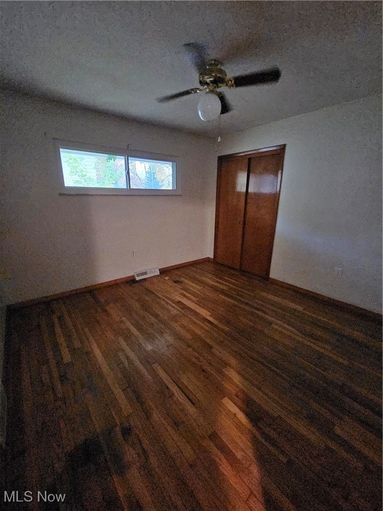 945 West Schaaf Road Cleveland, OH 44109 - Photo 9 of 27 Unfurnished bedroom featuring dark wood-type flooring, a textured ceiling, a closet, and ceiling fan