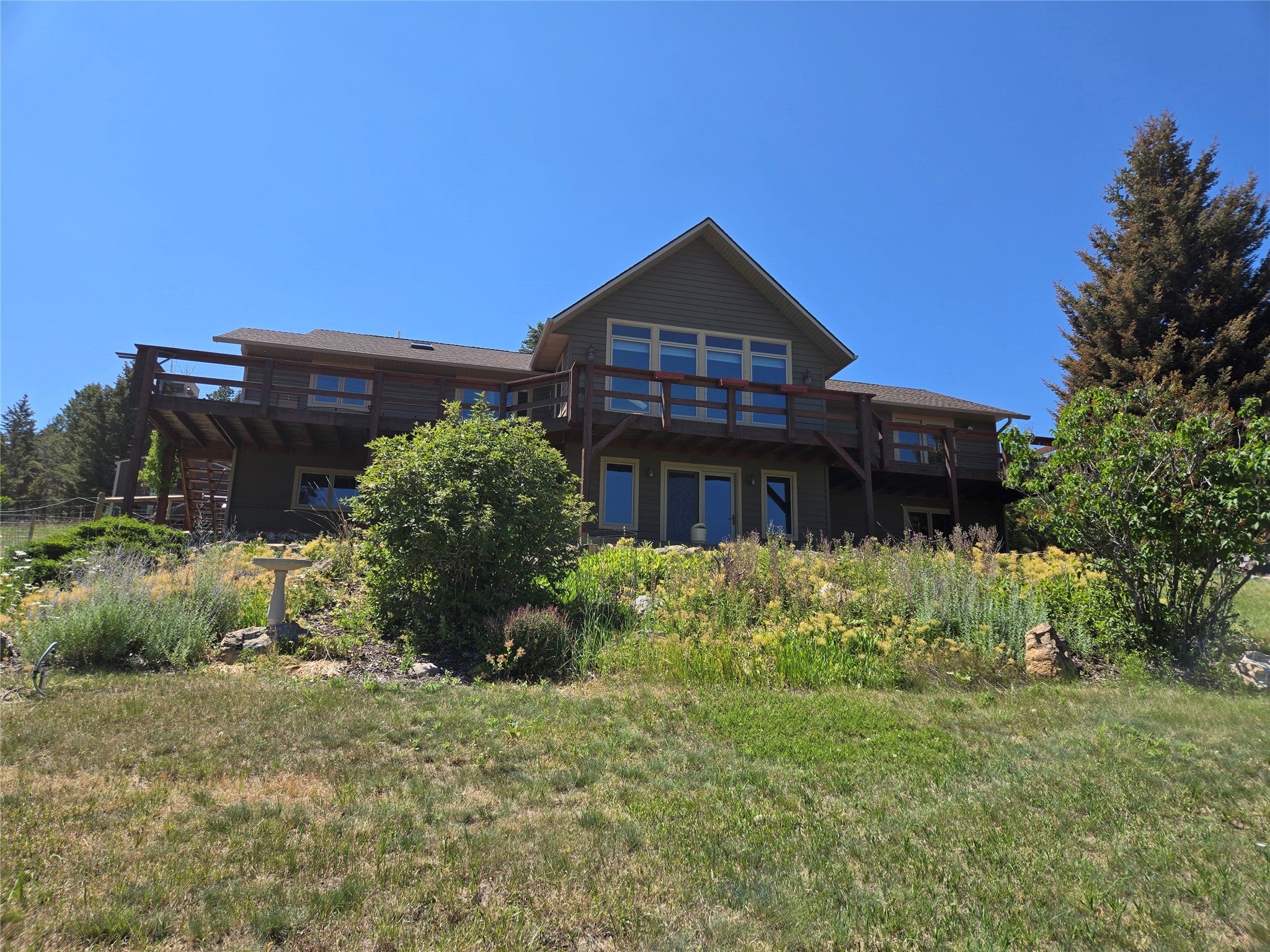 12 Hanson Road Clancy, MT 59634 - Photo 1 of 1 Back of house featuring a wooden deck and a lawn