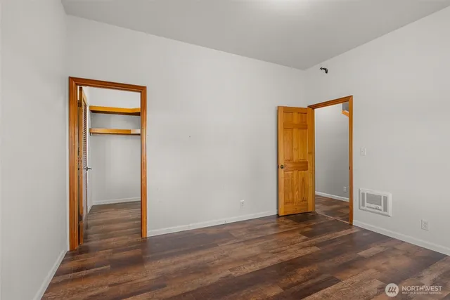 a view of an empty room with wooden floor and closet