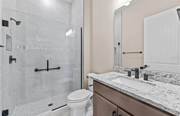 a bathroom with a granite countertop sink a toilet and shower