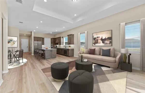 a living room with furniture kitchen view and a wooden floor
