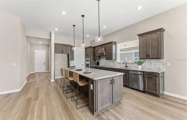 a kitchen with stainless steel appliances granite countertop a sink a stove and a wooden floors