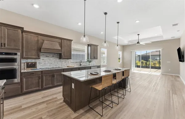 a kitchen with stainless steel appliances granite countertop a sink a stove and a wooden floors