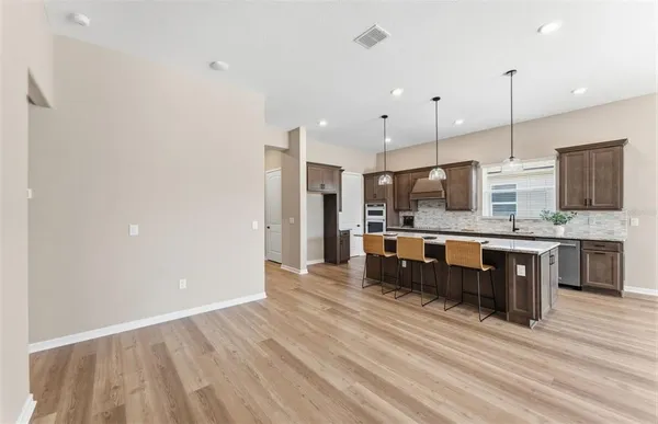 a large kitchen with stainless steel appliances kitchen island granite countertop a large stove a sink dishwasher and a refrigerator with wooden floor