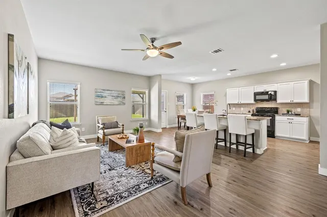 a living room with furniture kitchen view and a large window