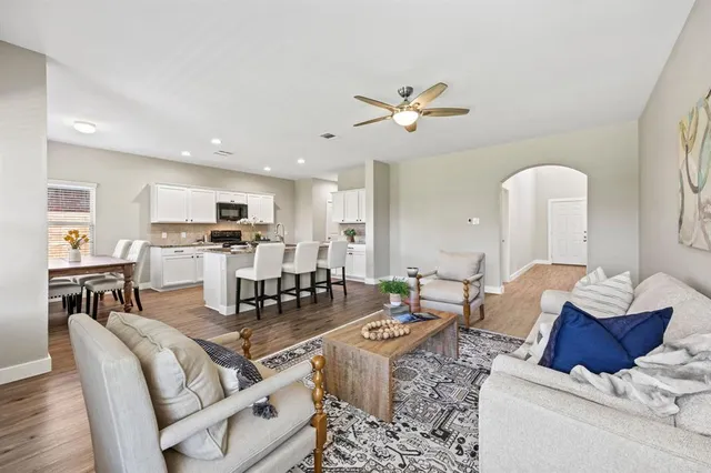 a living room with furniture kitchen view and a chandelier