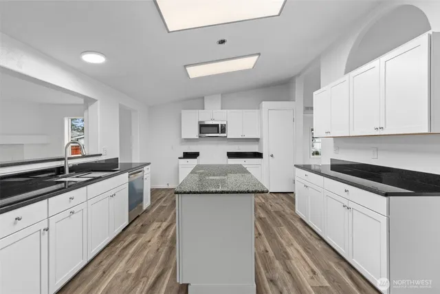 a large kitchen with granite countertop white cabinets and white stainless steel appliances