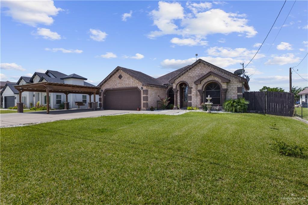 15501 East Davis Road Edinburg, TX 78542 - Photo 2 of 20 Exterior featuring brick facade, arched window details, a built-in garage with a dark-finish door, a covered carport structure, and a fenced side yard