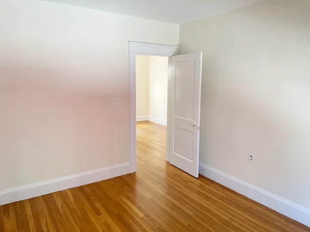 an empty room with wooden floor and door