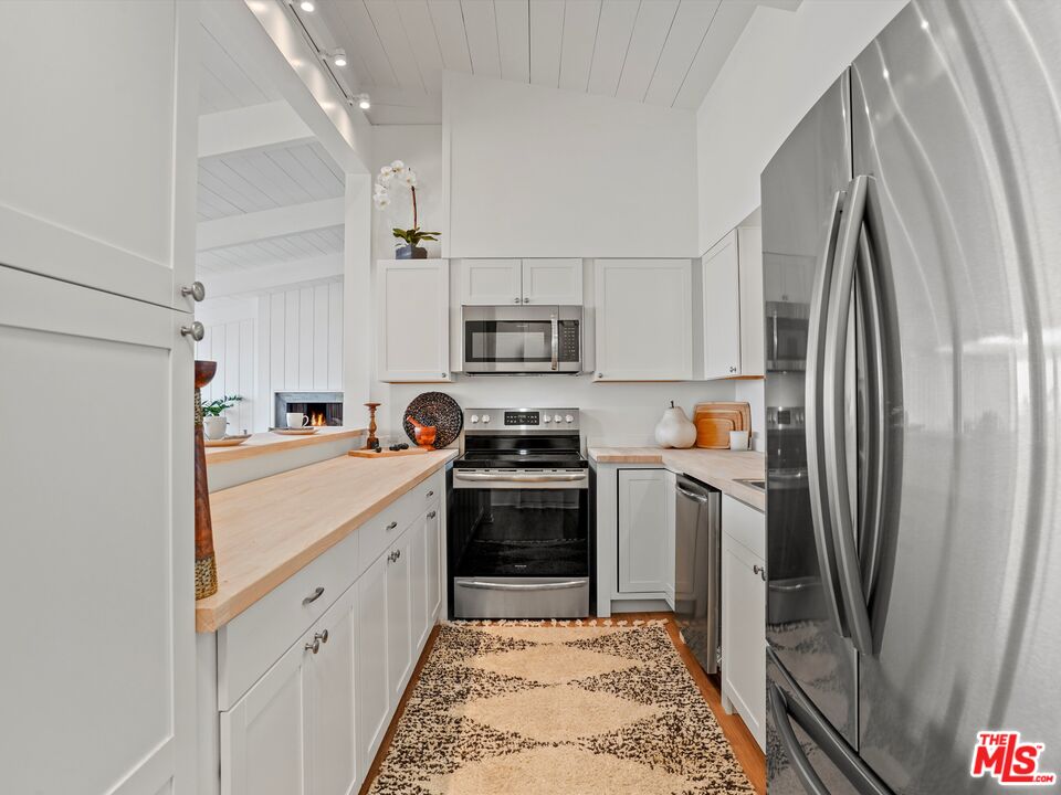 31284 Broad Beach Road Malibu, CA 90265 - Photo 11 of 31 a kitchen with white cabinets and stainless steel appliances