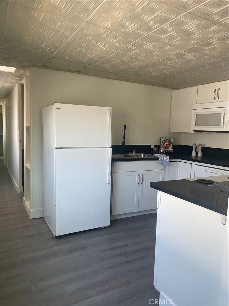 32802 Valle Road, Unit 135 San Juan Capistrano, CA 92675 - Photo 3 of 26 a kitchen with granite countertop a refrigerator a sink and white cabinets