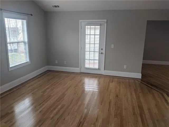 an empty room with wooden floor and windows