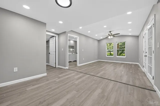 an empty room with wooden floor and windows