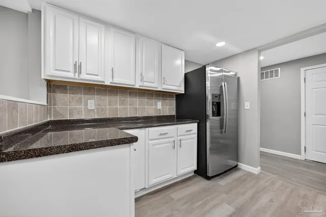 a kitchen with granite countertop a refrigerator sink and cabinets