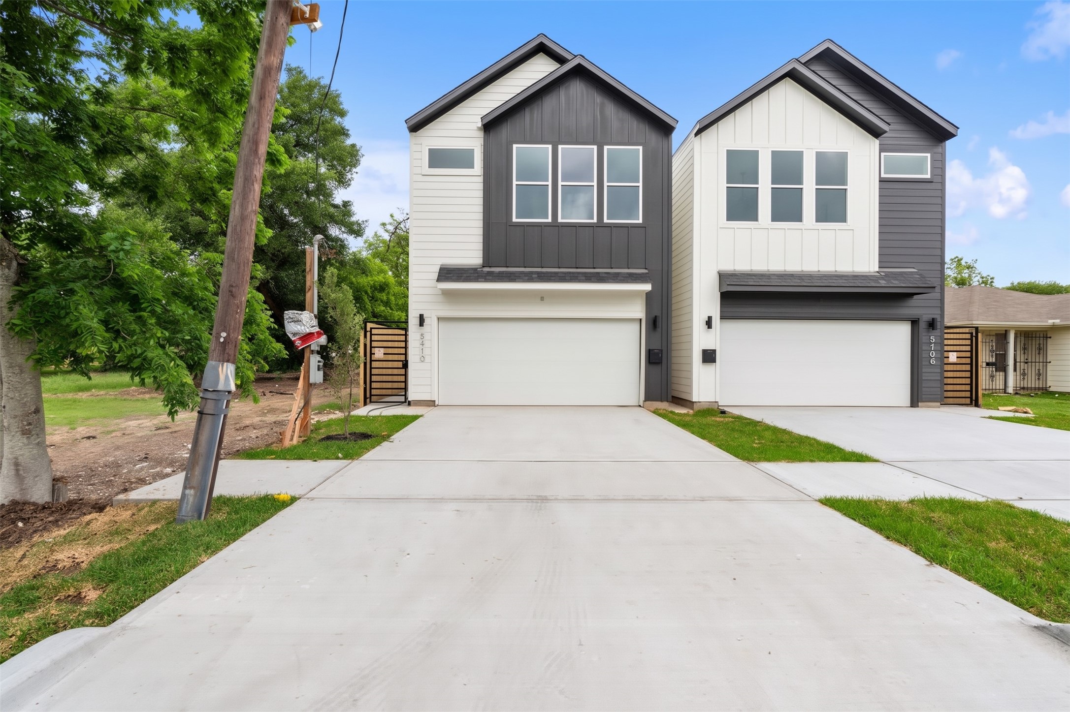6408 Foster Street Houston, TX 77021 - Photo 36 of 39 Bold modern elevation — charcoal vertical accent siding, white board-and-batten contrast, expansive dual driveways, and private wrought-iron side gates.