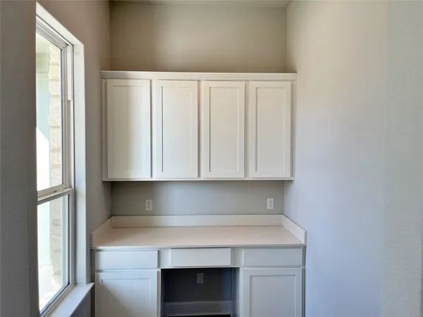 a view of kitchen with granite countertop white cabinets and a window