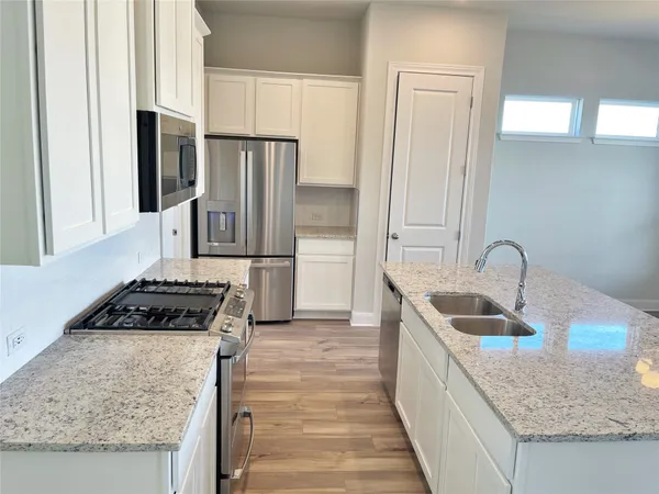 a kitchen with granite countertop a sink stove and refrigerator