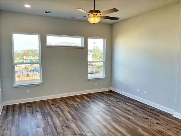 a view of an empty room with window and wooden floor