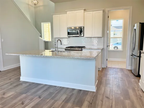 a kitchen with stainless steel appliances a sink wooden floor and cabinets