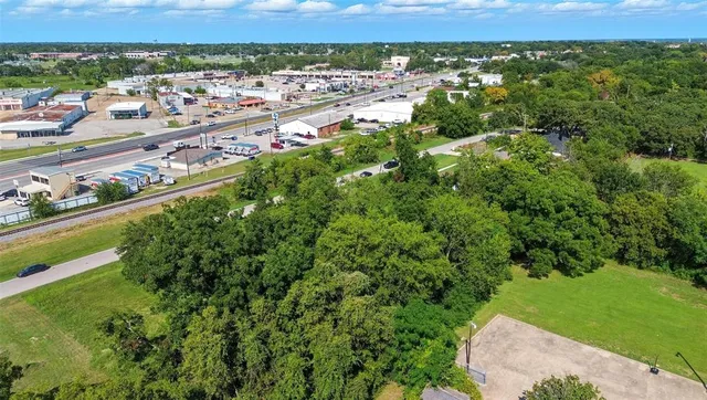 an aerial view of a residential houses with outdoor space and trees
