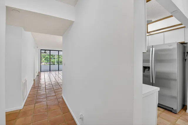a view of a hallway with wooden floor and a refrigerator