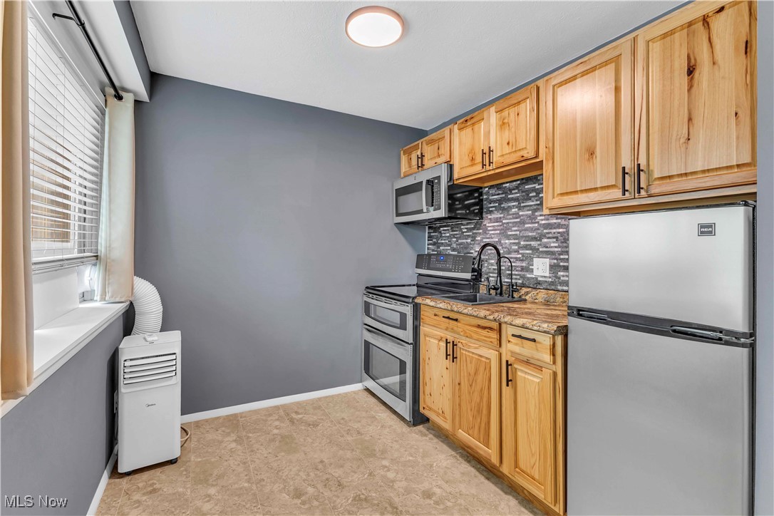 6640 Pearl Road, Unit 104 Cleveland, OH 44130 - Photo 6 of 31 Kitchen featuring stainless steel appliances, decorative backsplash, light brown cabinets, a sink, and baseboards