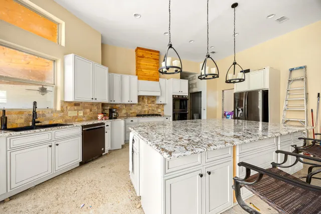 a kitchen with stainless steel appliances granite countertop a sink a stove and a wooden floor