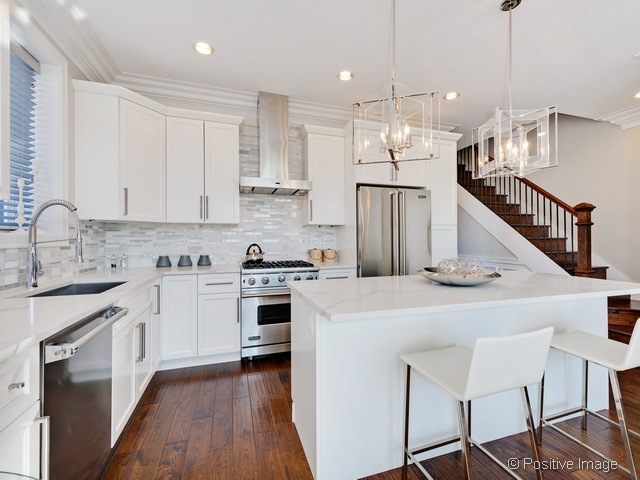 1430 West Fillmore Street, Unit 3W Chicago, IL 60607 - Photo 8 of 17 a kitchen with kitchen island a stove a sink a refrigerator and white cabinets with wooden floor