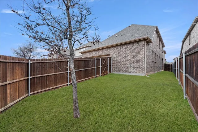 a view of a backyard with wooden fence and large trees