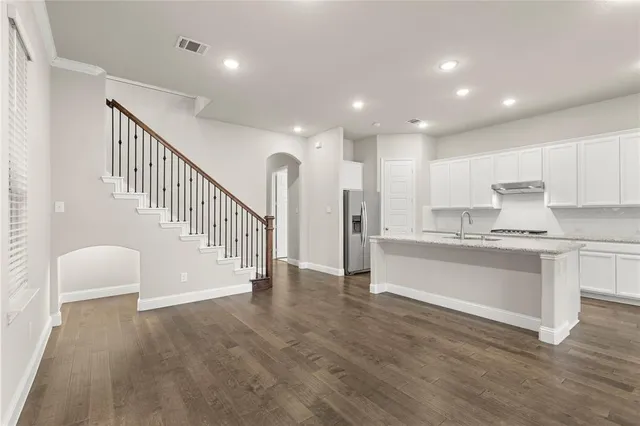 a kitchen with stainless steel appliances a refrigerator and white cabinets