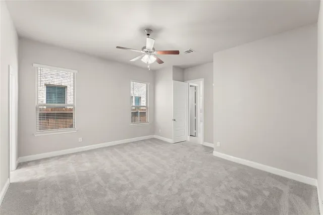 an empty room with chandelier fan and windows