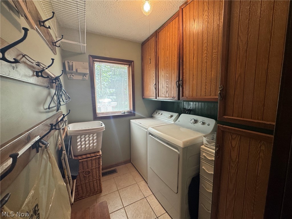 8201 Orchard Road Painesville, OH 44077 - Photo 36 of 45 Dedicated laundry space featuring ceramic tile flooring, wood-finish cabinetry, a window with blinds, a wall-mounted coat rack, and overhead wire shelving
