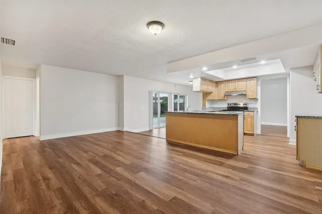 a view of a kitchen with kitchen island a sink wooden floor and a counter top space