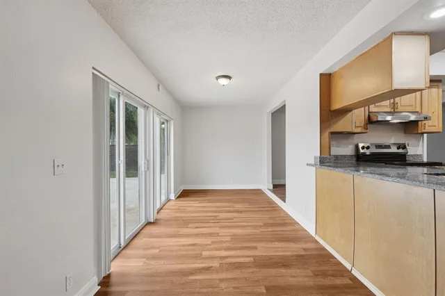a kitchen with kitchen island granite countertop wooden floors and wide window