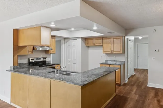a kitchen with granite countertop a sink and dishwasher cabinets with wooden floor