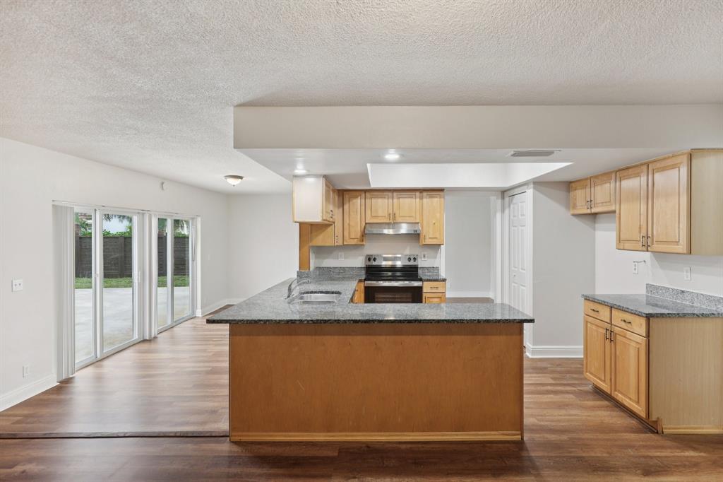 1541 Northwest 9th Street Boca Raton, FL 33486 - Photo 26 of 63 a kitchen with kitchen island granite countertop wooden floors and wide window
