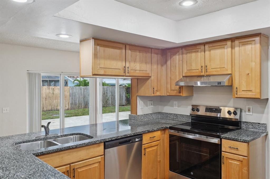 1541 Northwest 9th Street Boca Raton, FL 33486 - Photo 27 of 63 a kitchen with stainless steel appliances granite countertop a sink a stove and a microwave
