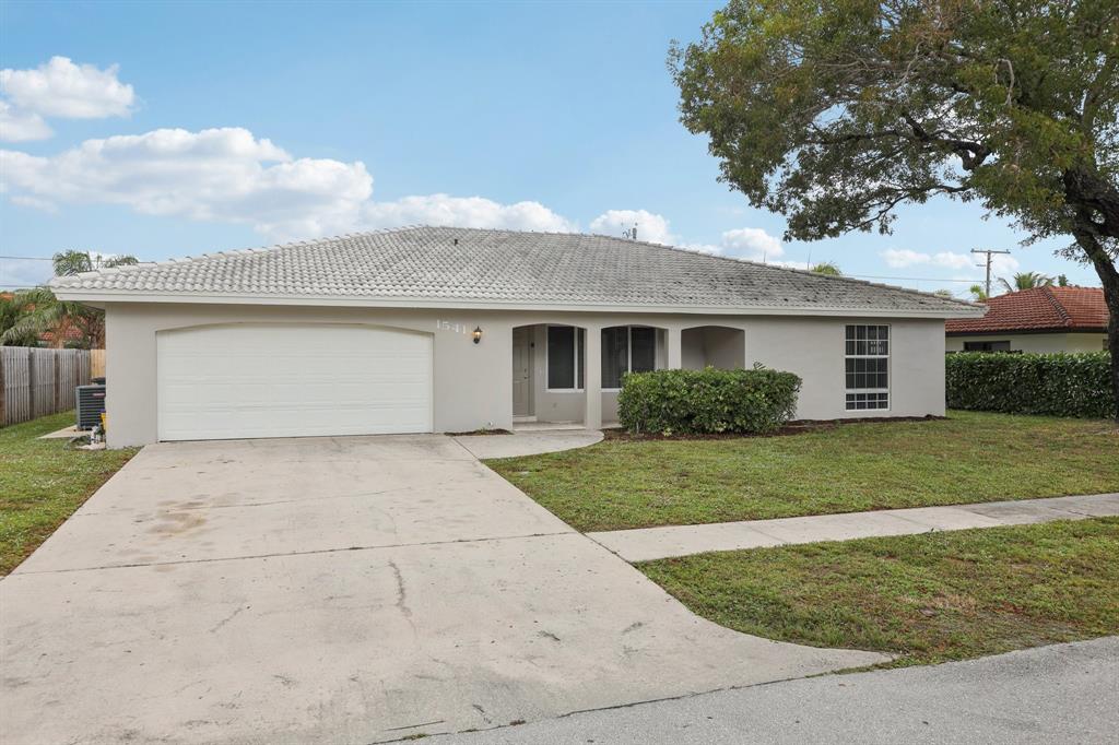 1541 Northwest 9th Street Boca Raton, FL 33486 - Photo 3 of 63 a front view of a house with a yard and garage